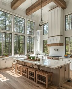 a large kitchen with lots of windows and wooden flooring, along with an island in the middle