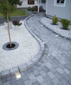 an outdoor patio area with gravel and stone paversed walkways, potted trees and landscaping lighting