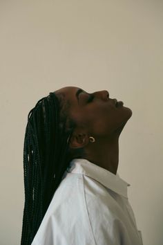 a woman with dreadlocks looking up into the sky while wearing a white shirt