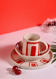 a cup and saucer sitting on top of a plate next to a palm leaf