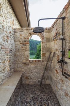 a bathroom with stone walls and an open window in the wall, next to a shower head