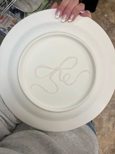 a person holding a white plate with the letter g on it