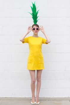 a woman in a yellow dress with a green pineapple on top of her head