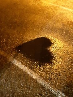 the shadow of a street sign is shown on the ground at night time, with light reflecting off it's surface