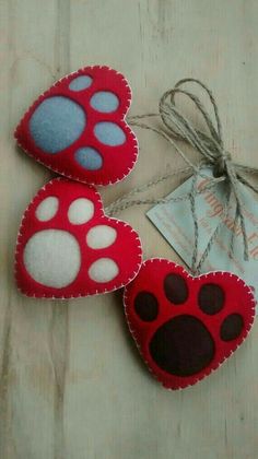 three red and white heart shaped ornaments with paw prints