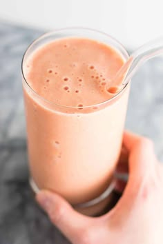 a hand holding a glass with a smoothie in it