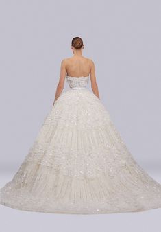 a woman in a white wedding dress looking down at the floor and back of her gown