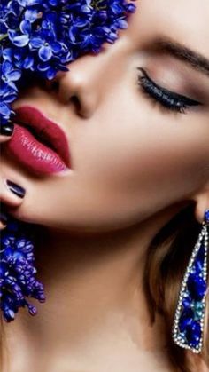 a beautiful woman with blue flowers on her face and red lipstick, wearing large earrings