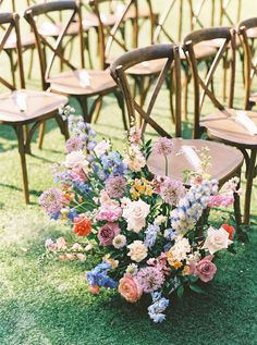 a bunch of chairs sitting on top of a grass covered field next to each other