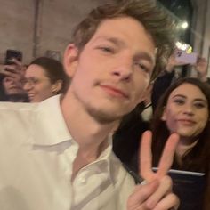 a man making the v sign with his fingers while standing in front of a group of people