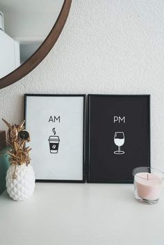 two framed pictures sitting on top of a white table next to a candle and a pineapple