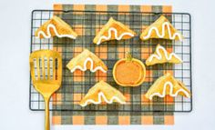 some cookies are on a cooling rack with a spatula next to it and an orange slice