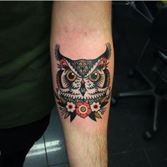 an owl tattoo on the arm with flowers