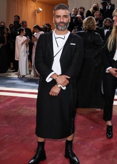 a man in a tuxedo standing on a red carpet