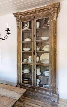 an old china cabinet with dishes in it