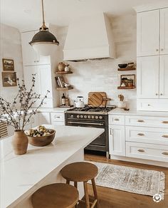 a kitchen with white cabinets and wooden stools next to an island in the middle