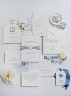 the wedding stationery is laid out on top of each other, with blue ribbon and white flowers