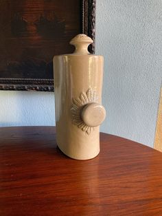 a ceramic jar sitting on top of a wooden table next to a framed painting in a frame