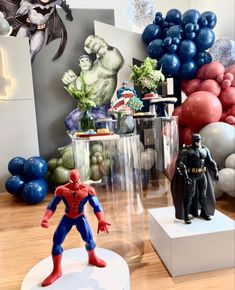 two action figures are on display in front of balloons and other decorations at a birthday party