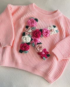 a pink sweater with flowers on it