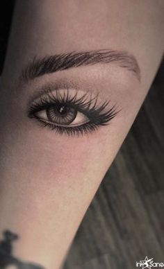 an eye with long lashes is shown on the arm