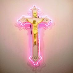 a neon cross is shown on a pink background