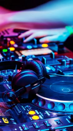 headphones on top of a dj's turntable in front of colorful lights