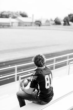 a young man sitting on top of a bench holding a soccer ball