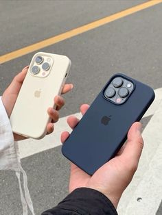 a person holding an iphone case in their hand next to the street with two other phones