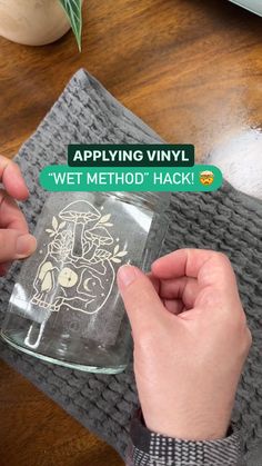 a person holding a glass jar with a sticker on it that says applying vinyl wet method hack