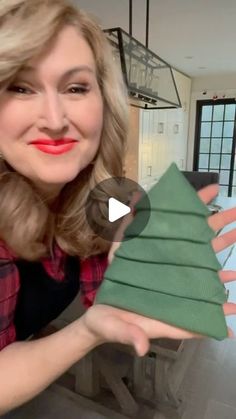 a woman holding up a folded christmas tree