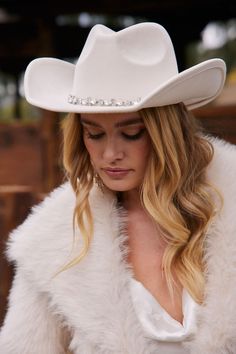 a woman wearing a white cowboy hat with pearls on the brim and long hair