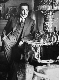 black and white photograph of a man sitting in front of a table with vases on it