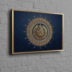 an arabic calligraphy on a blue background with gold frame hanging on a brick wall