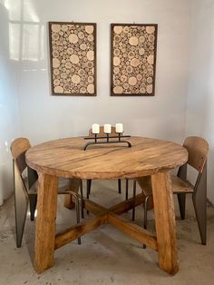 a wooden table and chairs in a room with two paintings on the wall behind it