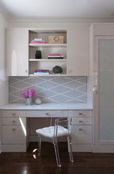 a white desk and chair in a room with wooden floors, built - in bookcases and cabinets