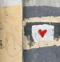 a red heart is painted on the side of a building with paint peeling off it