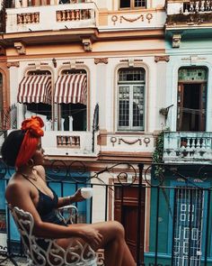 a woman sitting on top of a chair in front of a blue and white building