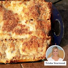 a square casserole dish with cheese and meat on the bottom, sitting on a blue plate next to a woman's face