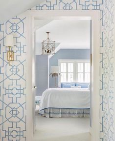 an open door leading to a bedroom with blue and white wallpaper