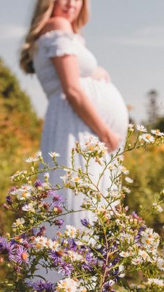 a pregnant woman standing in a field of wildflowers