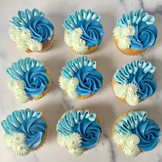 six cupcakes with blue and white frosting on top of a marble table