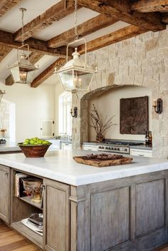 an open book shows a kitchen with stone walls and wood beams, along with a large center island