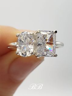 three stone diamond ring being held up by someone's hand in front of the camera