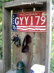 a wooden sign with sunglasses and other items hanging on it's side in front of trees