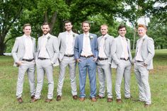 a group of men standing next to each other in front of some trees and grass