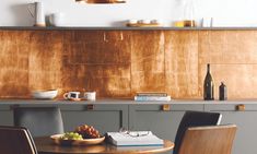 a table with two chairs and a bowl of fruit on it in front of a counter