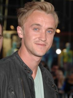 a close up of a person wearing a leather jacket and looking at the camera with a smile on his face