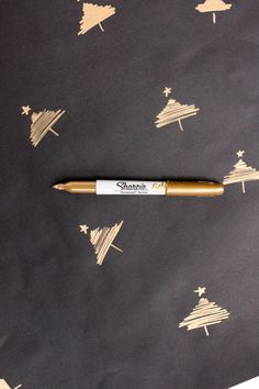 a pen sitting on top of a piece of paper with christmas trees drawn on it