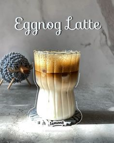 an eggnog latte in a glass on a table with the words, eggnog latte